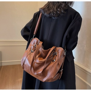 Detail of dark brown pebble leather tote bag with silver metal buckles and straps