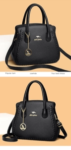 Detail of black litchi grain cowhide leather handbag with gold kangaroo logo and charms