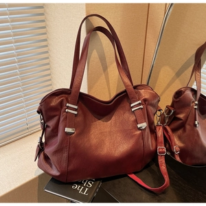 Detailed close-up of burgundy tote bag with metallic bar and adjustable strap