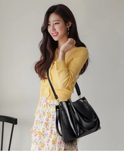 Detail of elegant black faux leather tote featuring golden hardware and adjustable strap