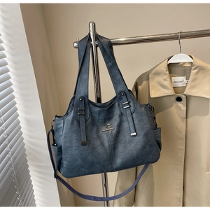 Detail of dark blue tote bag showing leather texture and gold kangaroo emblem