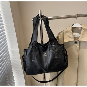 Close-up of black lychee-textured tote bag with silver kangaroo logo on a hanger