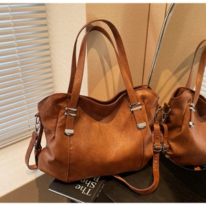 Close-up of brown leather bucket bag with silver buckles and adjustable strap details
