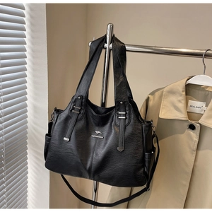 Close-up of black textured leather tote bag with silver logo and side pockets