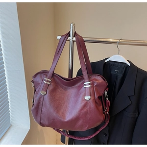 Detail of vintage burgundy tote bag with silver hardware on a display hanger