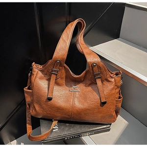 Detailed view of brown leather tote bag with metal logo and side pocket on stairs