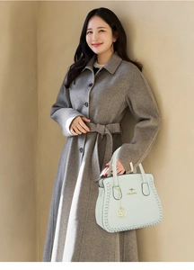 Detail of mint green leather handbag with woven texture and gold kangaroo emblem pendant