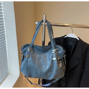 Close-up of blue-grey tote bag showing pebbled leather texture and silver hardware details