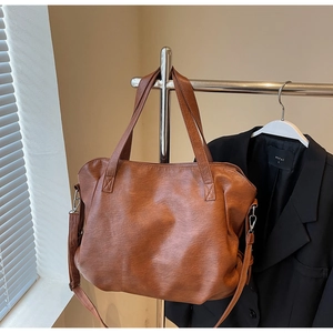 Detailed view of brown leather tote bag with sturdy handles and metal strap hooks