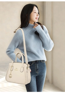 Detail of off-white lychee pattern leather tote bag with gold kangaroo logo on shoulder