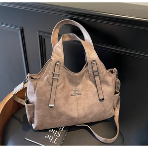 Close-up of vintage brown leather tote bag with brand logo and dual shoulder straps