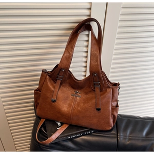 Detail of a brown leather tote bag with a kangaroo logo and durable top handles