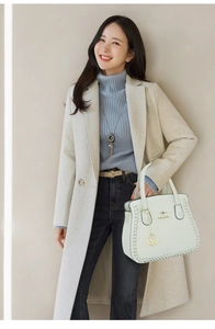 Detail of mint green handbag with metal kangaroo logo and woven leather trim