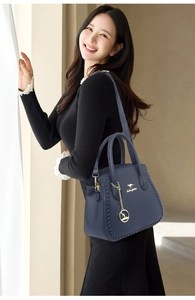 Detail view of navy blue tote with gold kangaroo hardware and woven leather edges