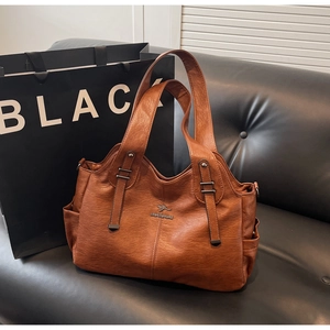 Close-up of brown tote bag side pocket and textured leather finish with metal logo