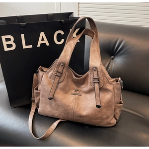 Detailed macro view of brown lychee-textured faux leather bag with kangaroo logo metal plaque