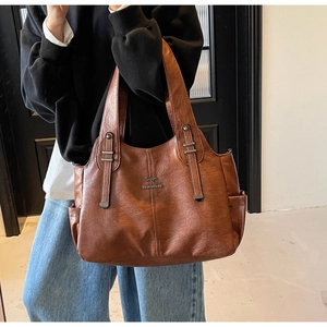 Detail of a brown leather tote bag with metallic kangaroo logo and side pocket