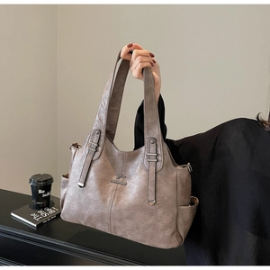 Detail of grey faux leather tote bag with embossed kangaroo logo and shoulder strap