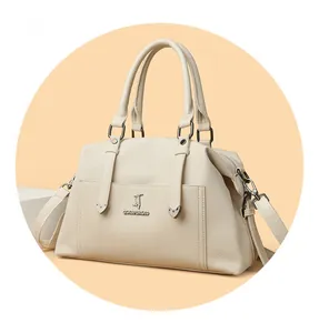 Détail du sac cabas en cuir crème avec breloque cœur et bandoulière amovible