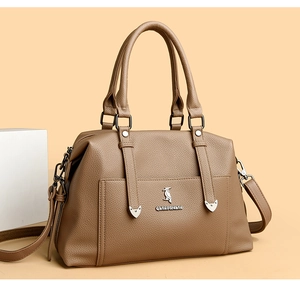 Gros plan sur le cuir grainé beige et le logo métallique de ce sac à main élégant