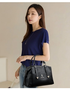 Détail d'un sac cabas en cuir grainé noir avec logo métallique et rivets argentés élégants