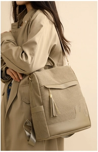 Detail of corduroy backpack with tassel charm and rabbit patch on a beige trench coat