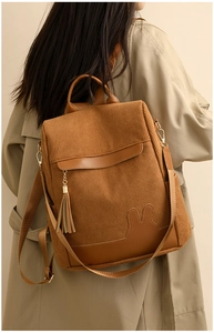 Detail of caramel corduroy backpack with rabbit ear design worn with a beige trench coat