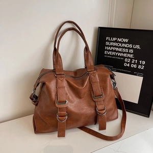 Grand sac à main en cuir marron avec sangles décoratives sur surface de marbre blanc