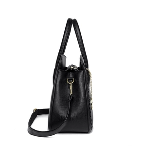 Black lychee leather handbag with gold hardware and woven details in a side profile view