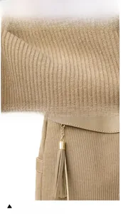 Close-up of khaki corduroy fabric texture and decorative tassel with golden chain