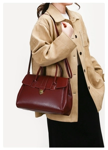 Detailed view of burgundy vintage leather tote with gold buckle worn by model