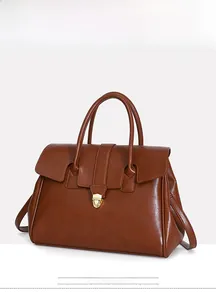Detail of vintage brown leather tote bag showing gold shield lock and dual handles