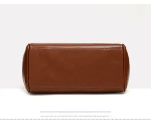 Detail view of the brown leather tote bag bottom with precise stitching and smooth texture