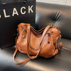 Caramel large capacity leather tote bag with silver hardware and adjustable strap on sofa