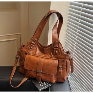 Detail of dark brown vintage PU leather tote bag with pocket and retro metallic hardware