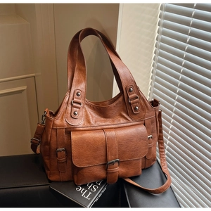 Detail view of brown vintage PU leather handbag with side buckle pockets on black seat