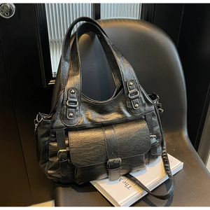 Detail of black soft leather handbag with buckle pocket and silver rivet handle straps