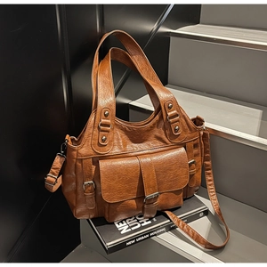 Close-up of vintage brown tote bag showing wrinkled leather texture and metal buckle detail