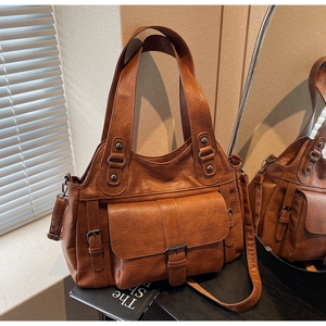 Close-up of vintage brown tote bag with decorative straps and magnetic flap outer pocket