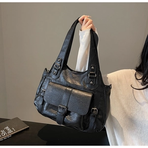 Detail of black faux leather tote bag with vintage metal buckles and front pocket
