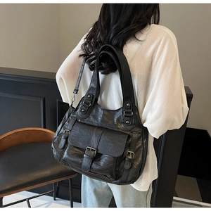 Detailed back view of a large black vintage faux leather tote bag worn by a model