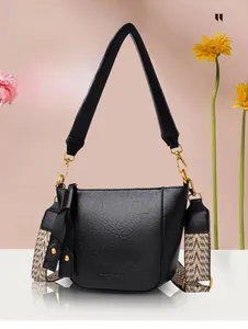 Detail view of black textured leather bucket bag with wide jacquard shoulder strap