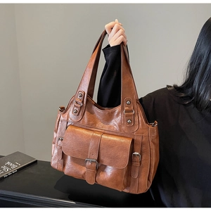 Detail of vintage brown textured leather handbag featuring large front flap pocket