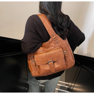 Detail of vintage brown leather tote bag with functional pockets and metal buckle strap