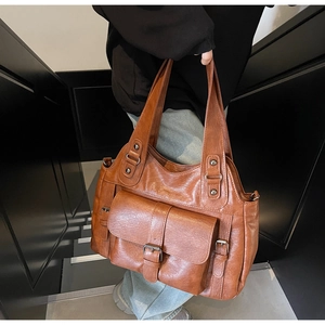 Detail of dark brown tote bag with vintage pebble leather texture and metal rivet accents