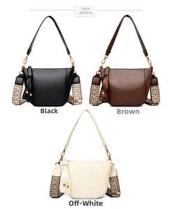 Close-up of saddle bucket bags in black, brown and cream with wide ethnic shoulder straps
