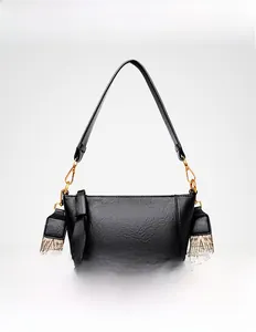 Close-up of black pebbled leather bucket bag with bohemian woven strap and gold hardware
