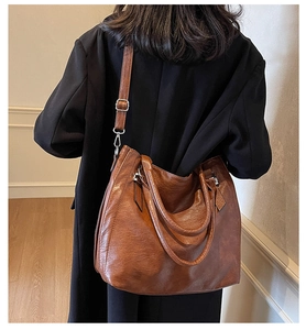 Detail of dark brown leather tote bag with lychee texture and adjustable shoulder strap