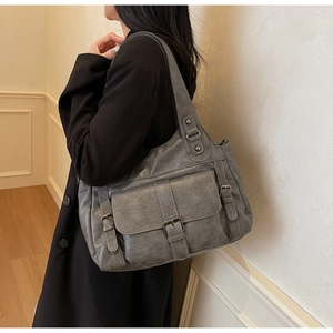 Detail of grey distressed PU leather tote with front flap pocket and industrial buckle accents