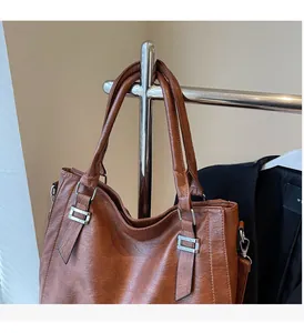 Detailed view of caramel leather shoulder bag with metallic buckle and retro texture